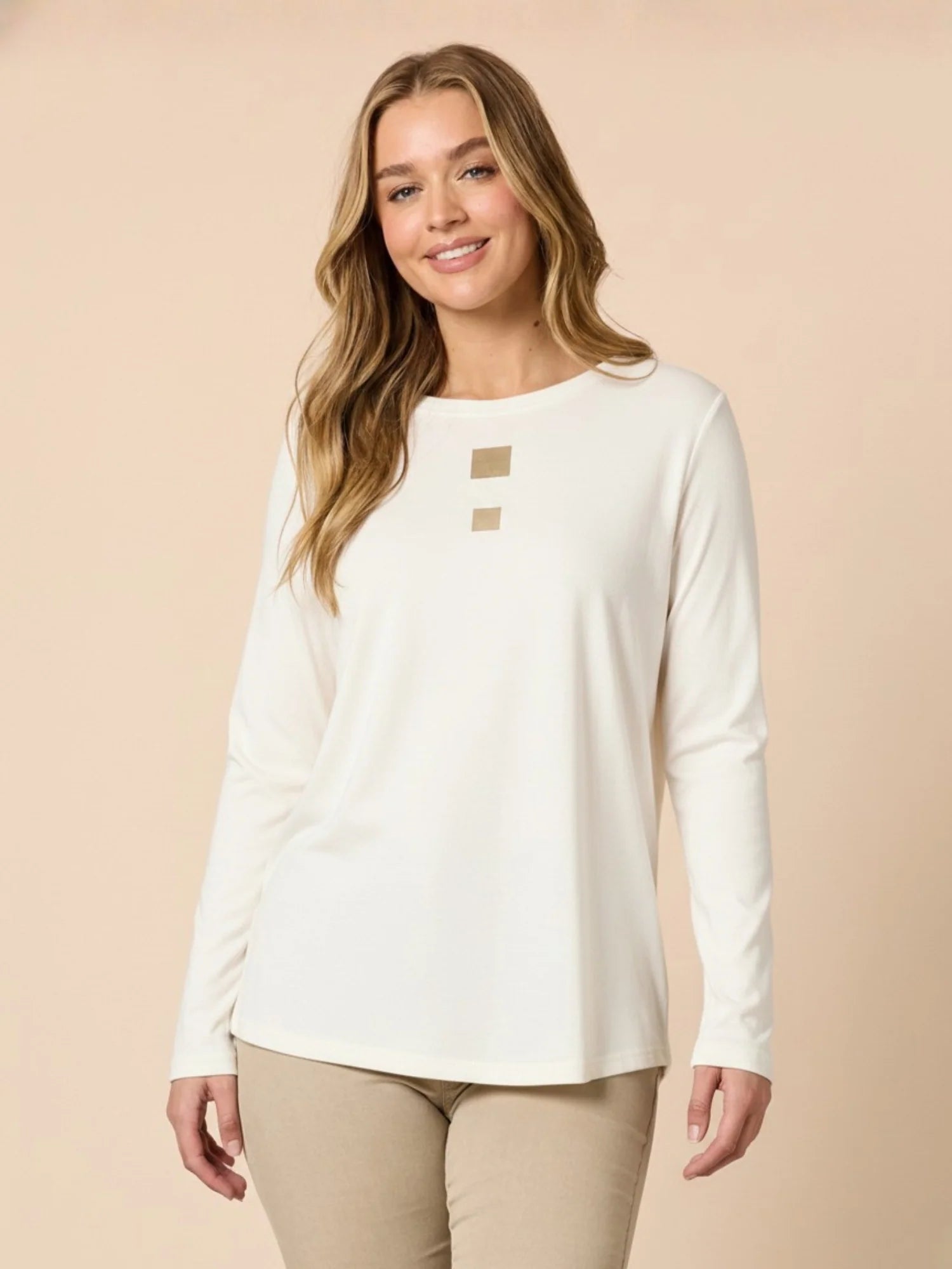 Woman wearing a Threadz white long-sleeve top with a beige background