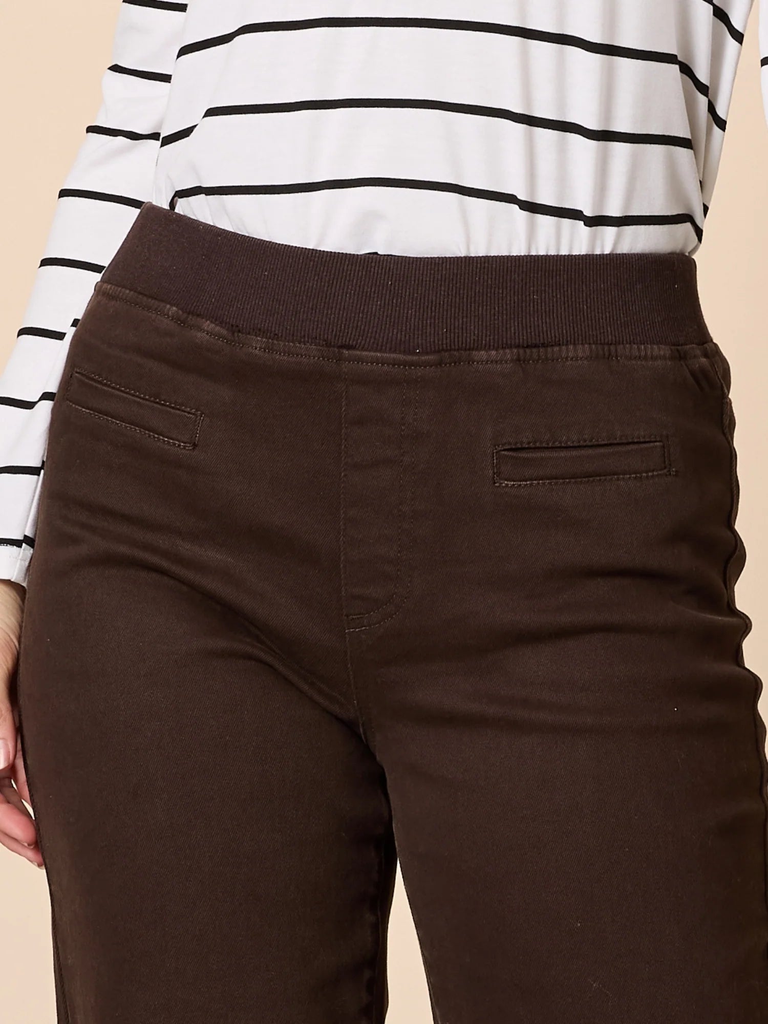 Collection of Woman wearing Threadz Brown pants worn with a white and black striped shirt on a beige background in a gallery layout