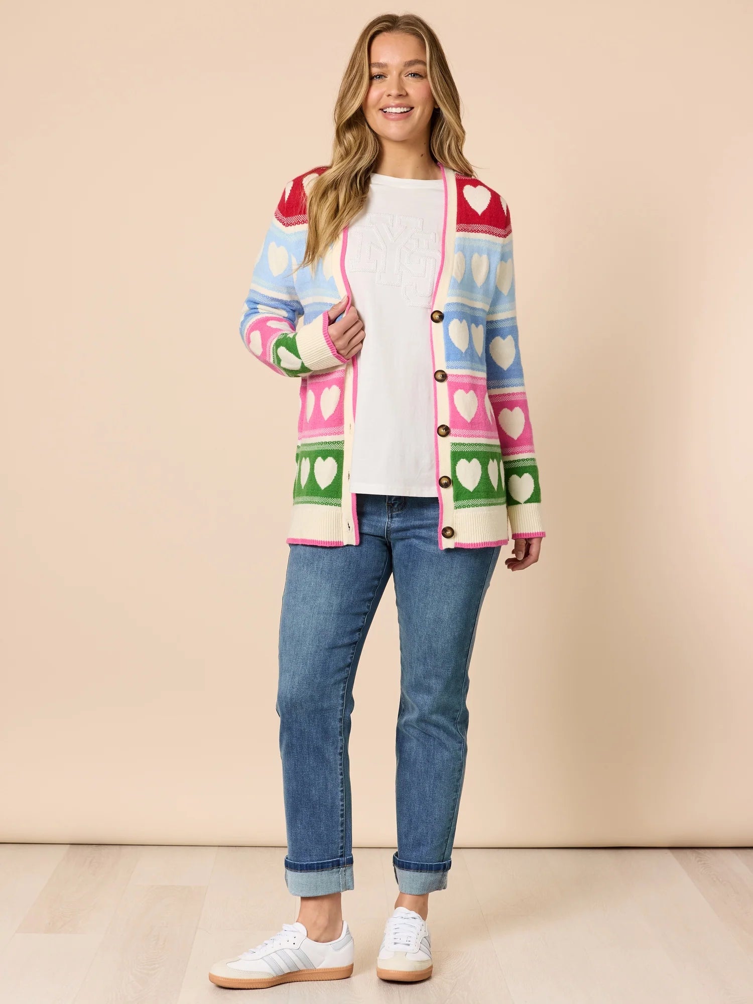 Woman wearing Threadz white long-sleeve top and blue jeans on a beige background