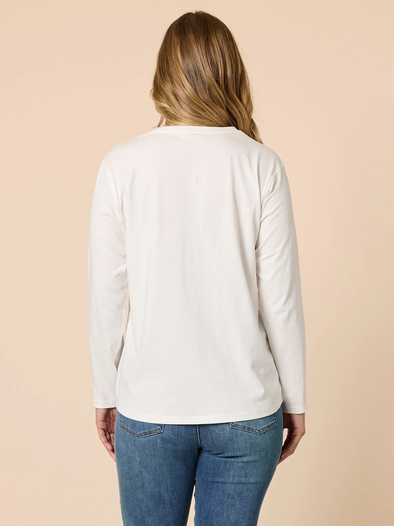 Person wearing a Threadz white long-sleeve shirt and blue jeans on a beige background