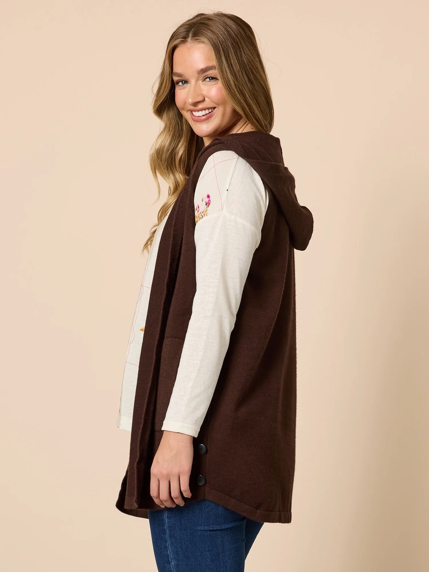 Woman wearing a Threadz brown vest over a white long-sleeve shirt with floral design on a beige background