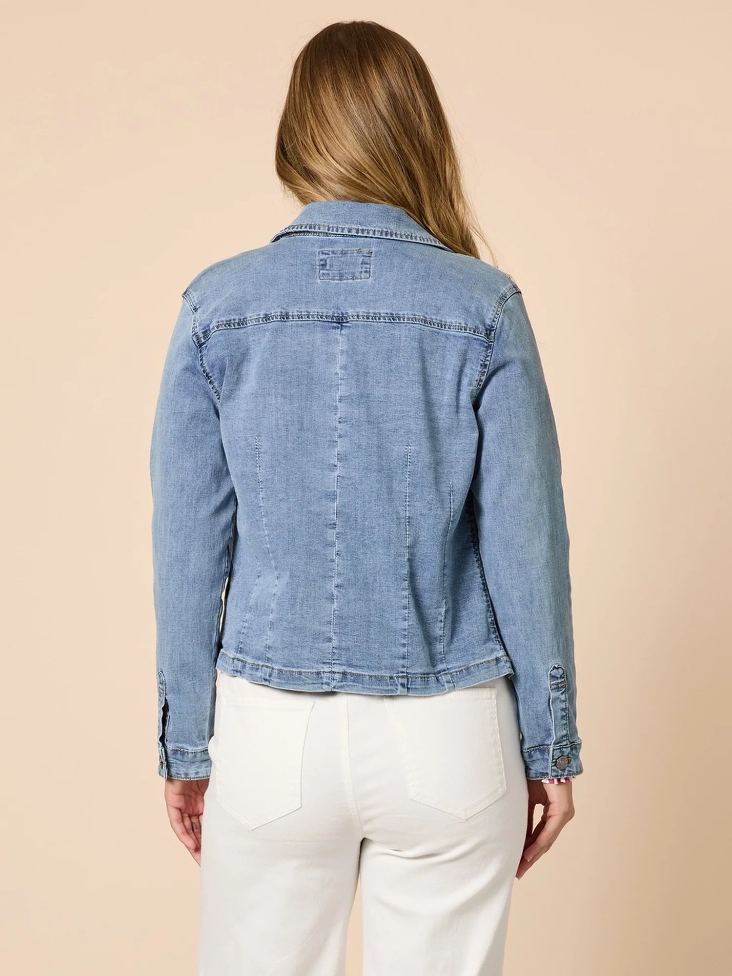 Woman wearing a Threadz blue denim jacket on a beige background