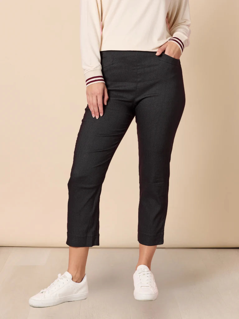 Woman wearing Threadz black pants and white sneakers on a beige background