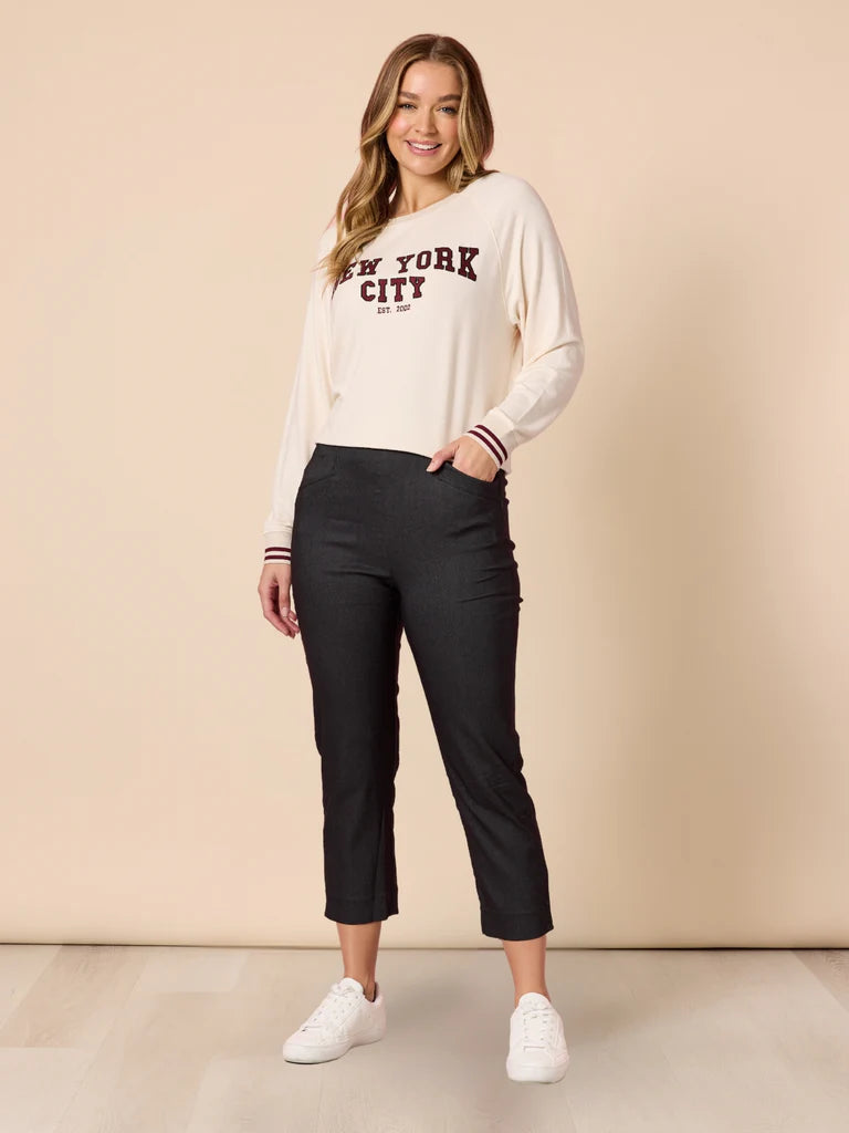 Image of Woman wearing a 'New York City' sweatshirt and Threadz black pants on a beige background