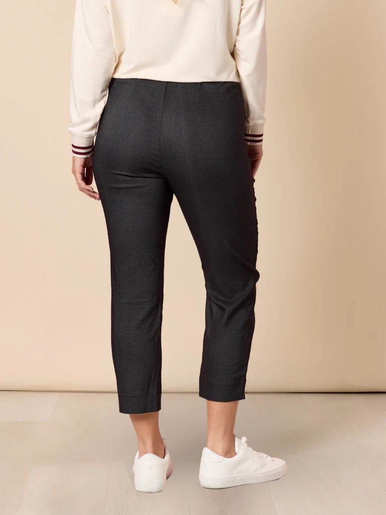 Image of Woman wearing Threadz black pants and white sneakers against a beige background