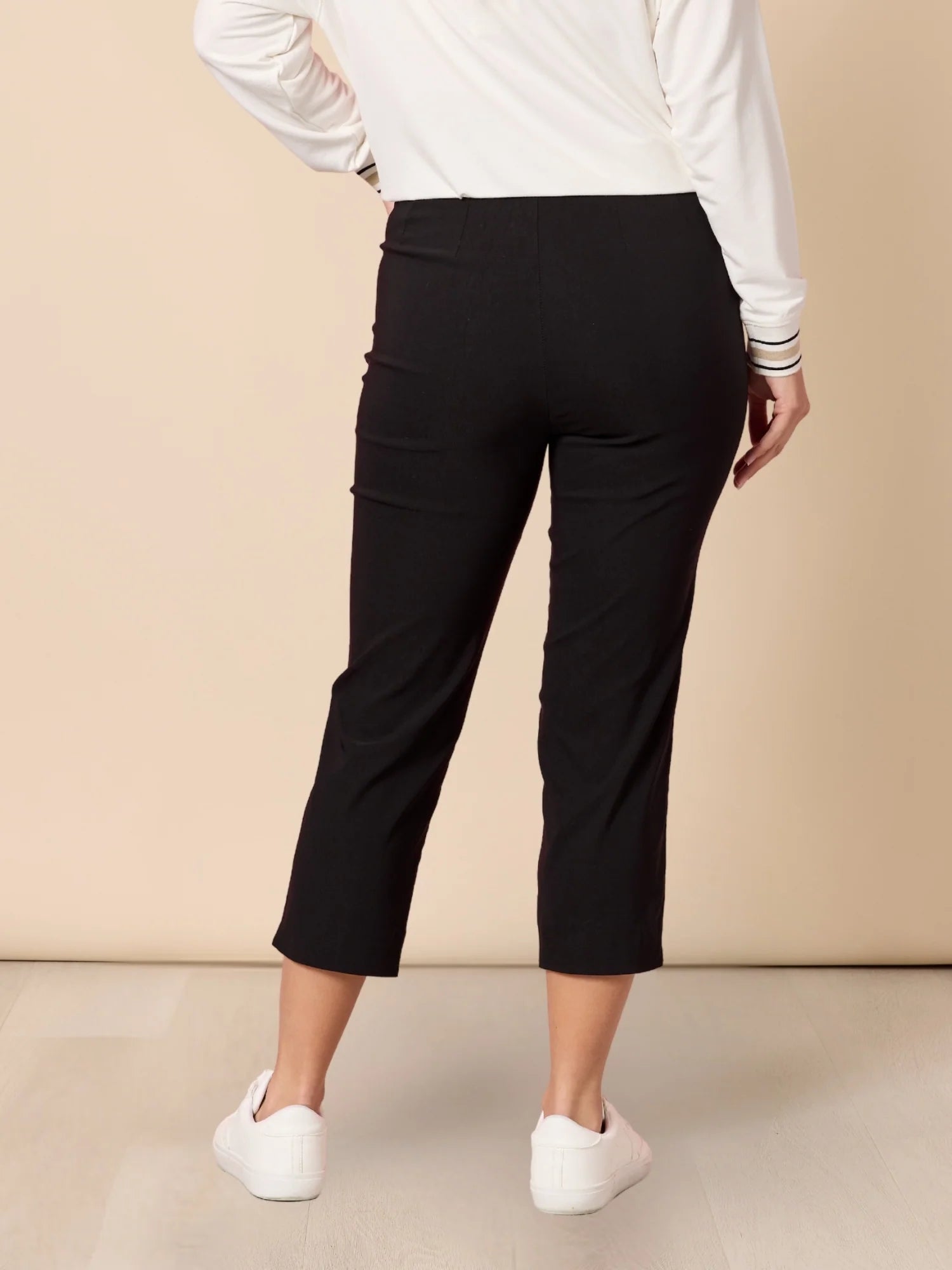 Women wearing Threadz black capri pants and a white long-sleeve shirt against a beige background