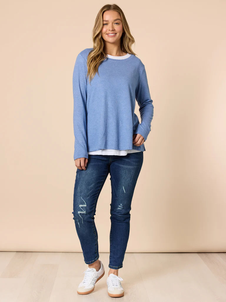 Woman wearing a Threadz blue sweater and jeans on a beige background