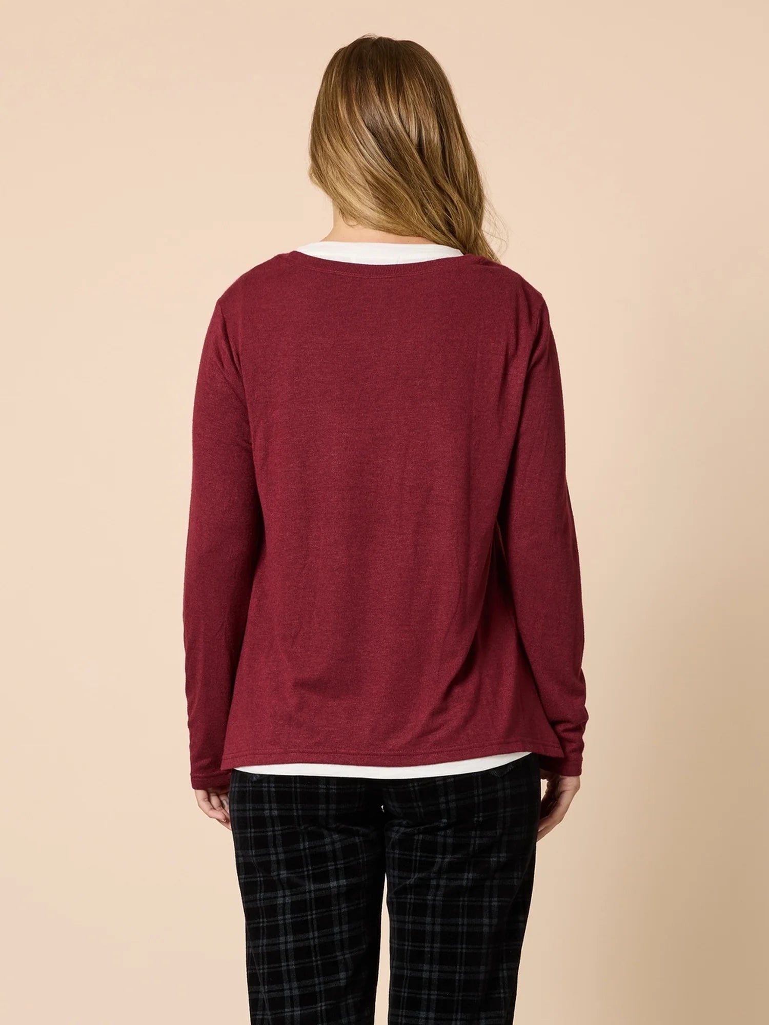 Person wearing a Threadz burgundy long-sleeve shirt and plaid pants on a beige background