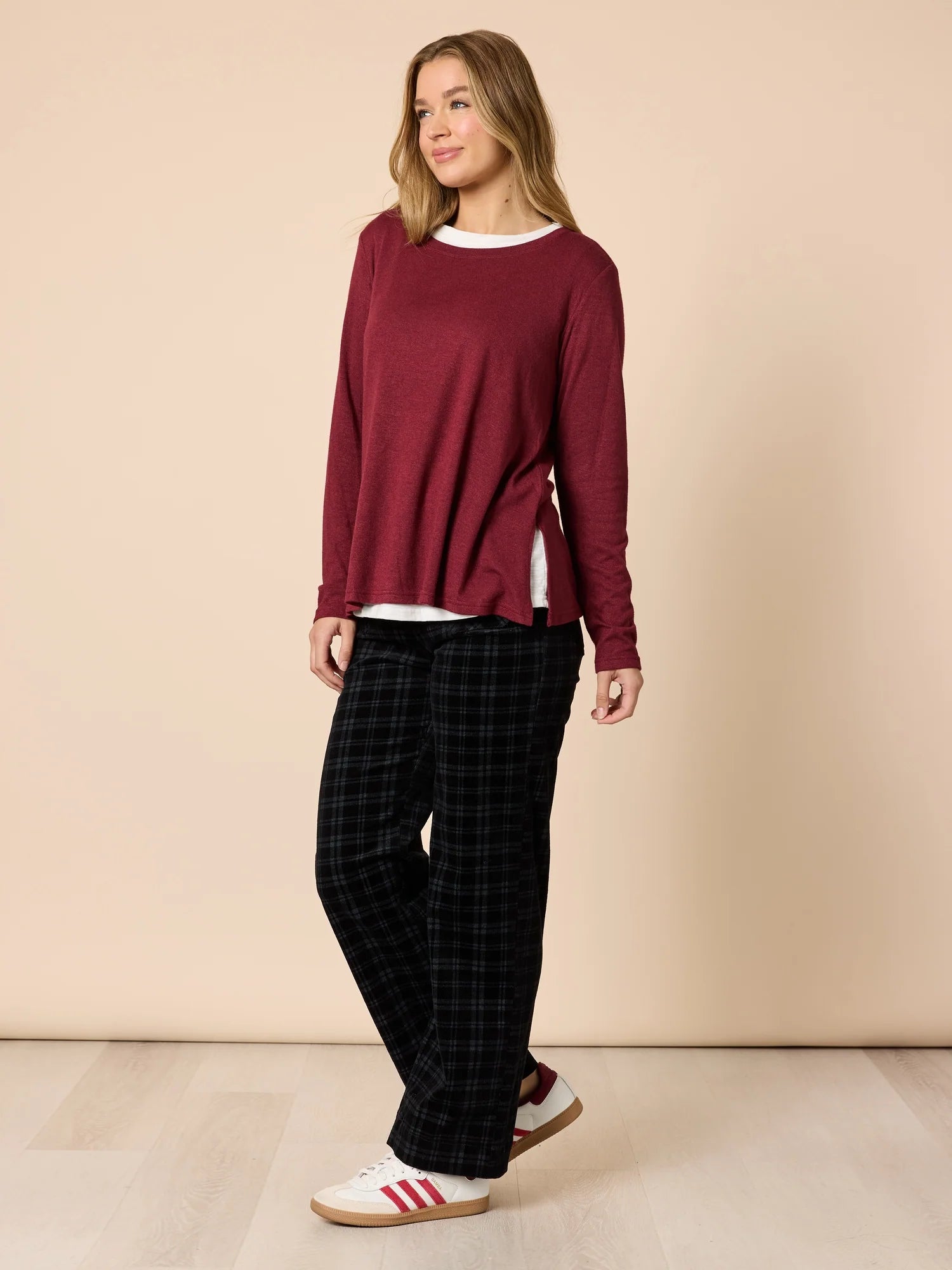Image of Woman wearing a Threadz burgundy long-sleeve top and black plaid pants on a beige background