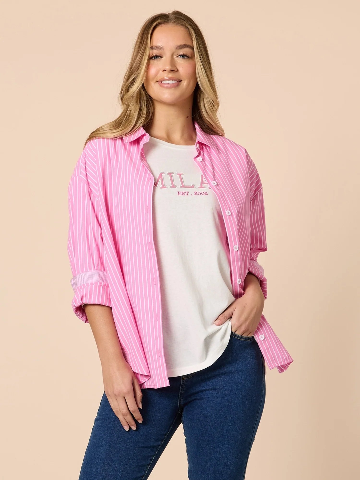 Woman wearing a Threadz white & pink stripe shirt with denim jeans on a beige background