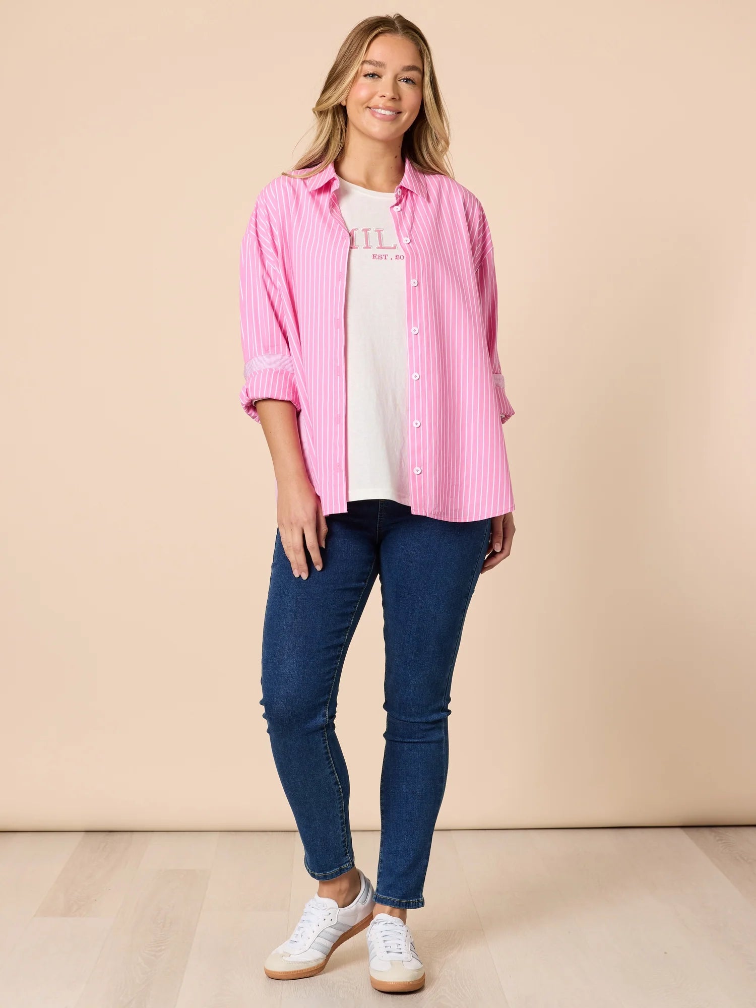 Collection of Woman wearing a Threadz white & pink stripe shirt with denim jeans on a beige background in a gallery layout