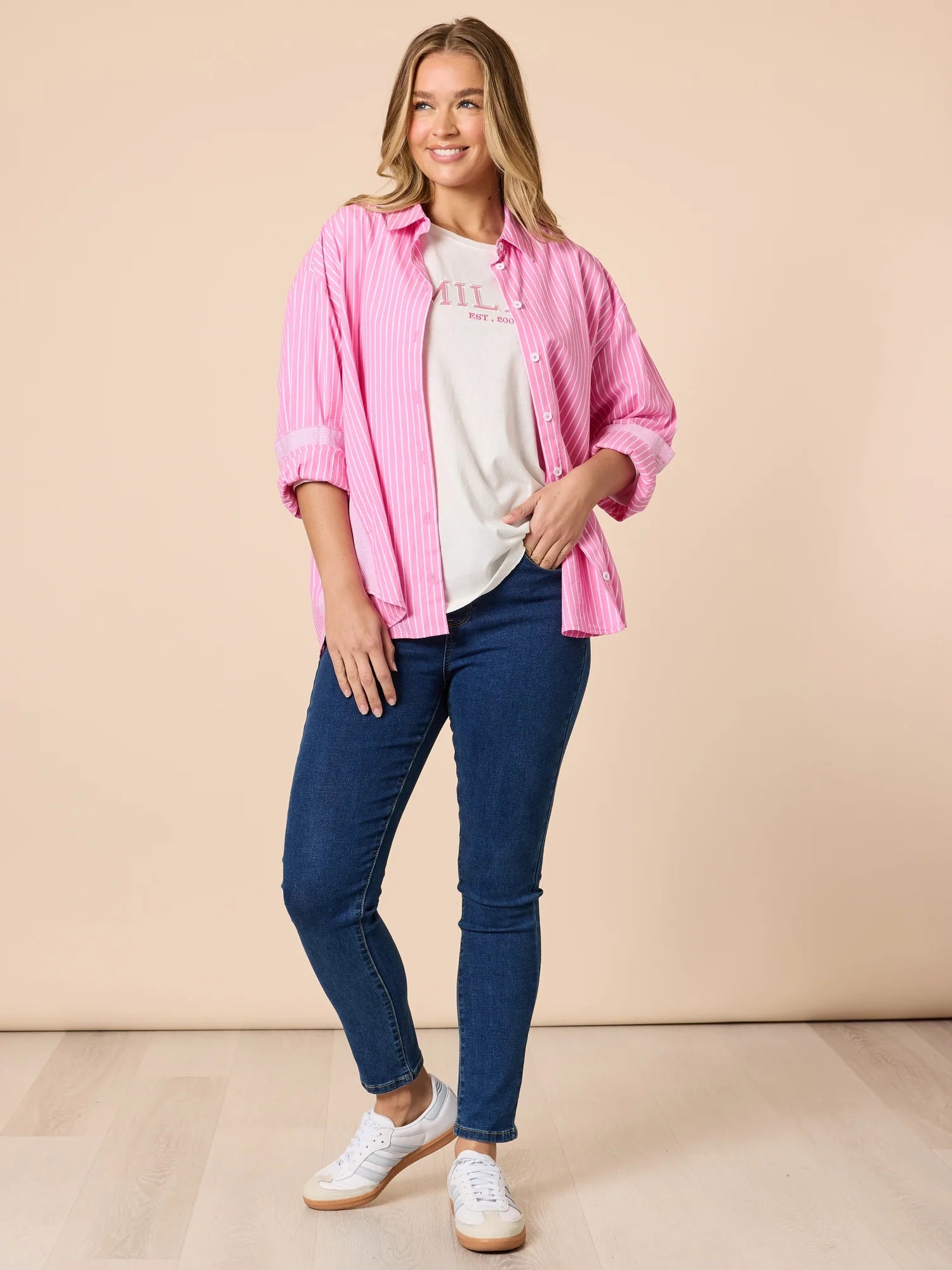 Collection of Woman wearing a Threadz white & pink stripe shirt with denim jeans on a beige background in a gallery layout
