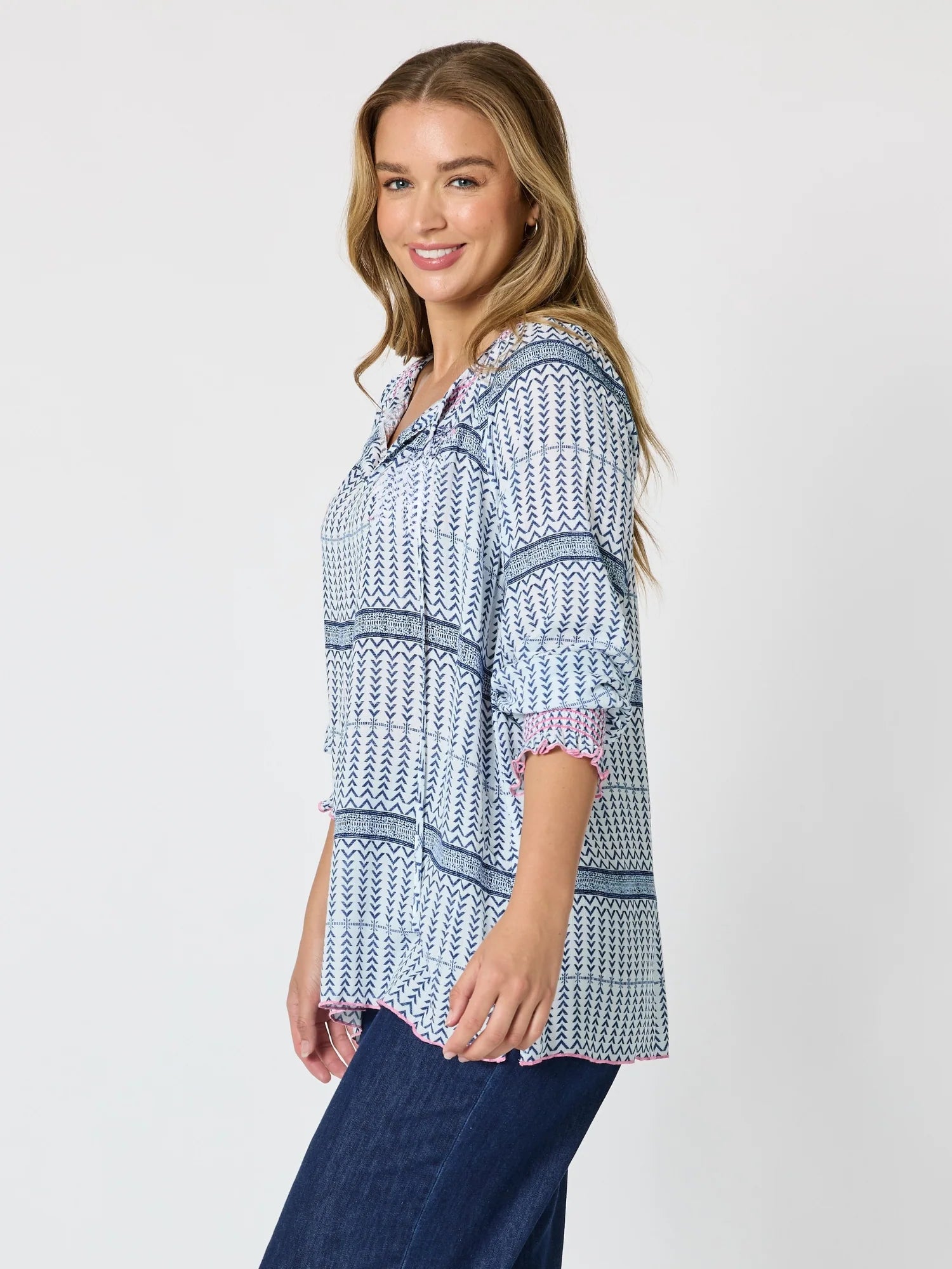 Image of A woman modeling a Threadz light blue and white patterned button-up shirt with three-quarter sleeves and dark blue jeans, photographed against a solid light gray background.