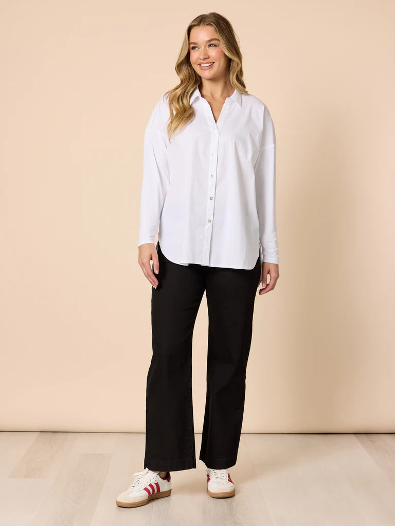 Image of Woman wearing a Threadz white shirt and Threadz black pants against a beige background