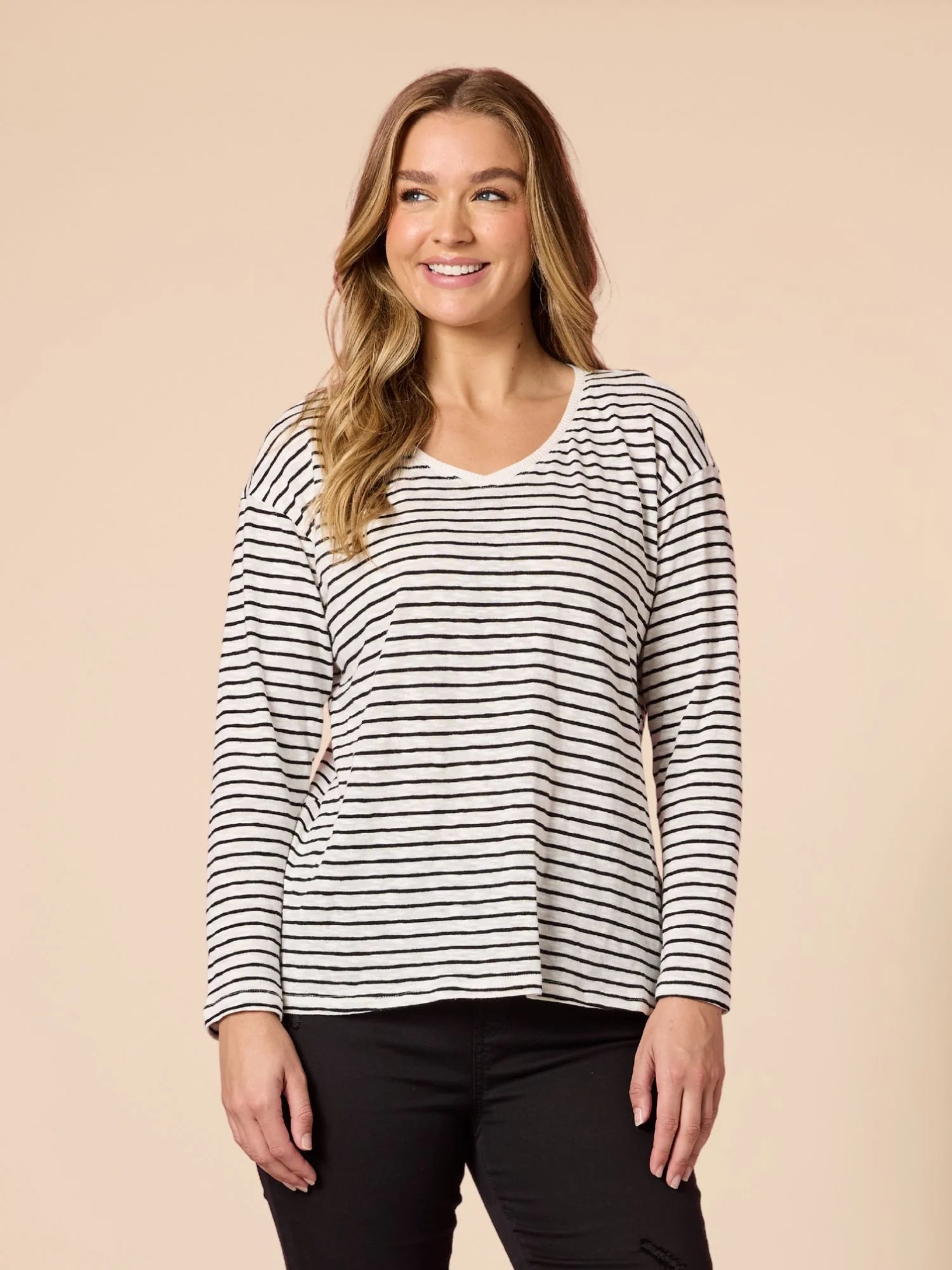 Image of Woman wearing a Threadz black and white striped long-sleeve shirt against a beige background