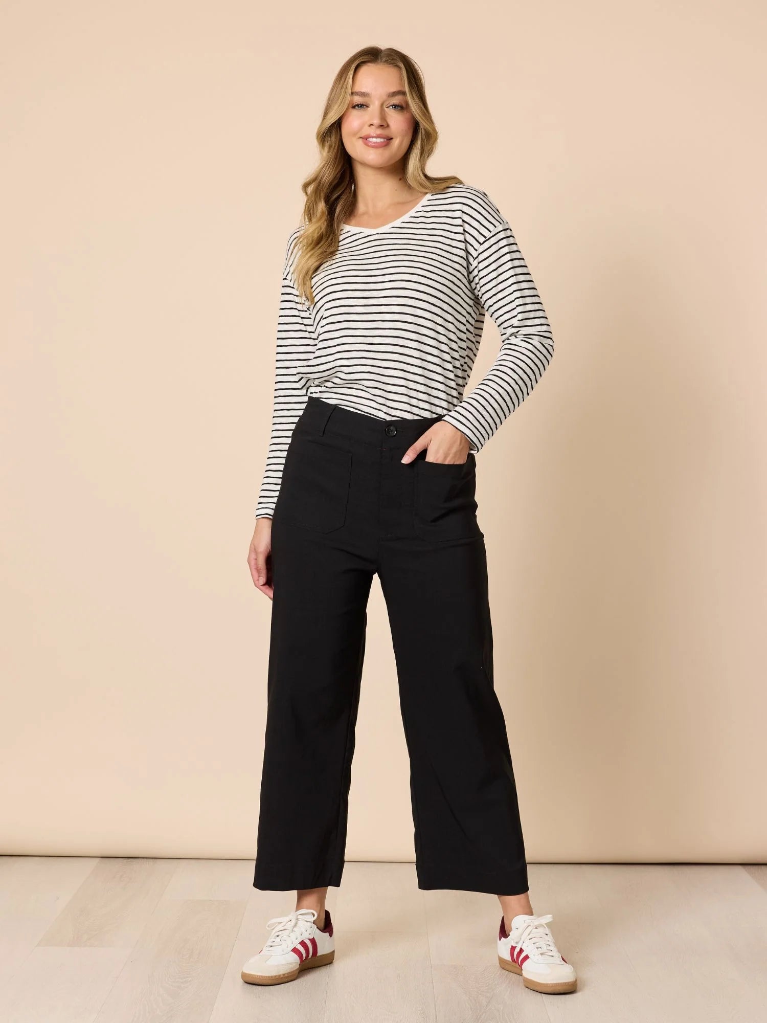 Woman wearing a Threadz striped long-sleeve top and black pants against a beige background
