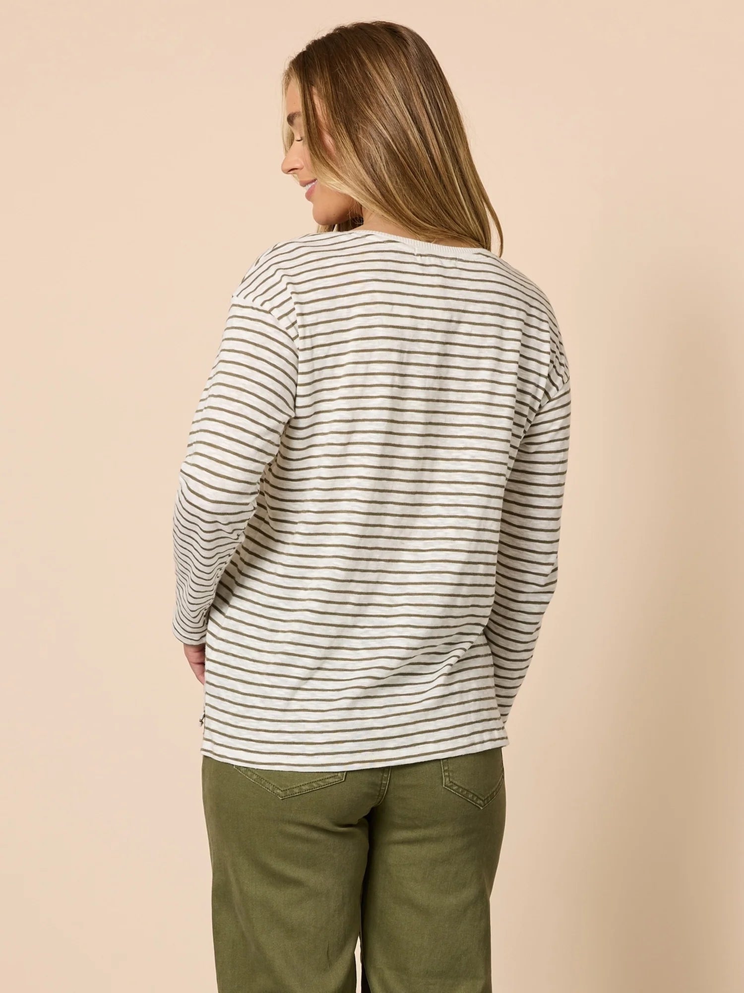 Image of Woman wearing a Threadz striped long-sleeve shirt and green pants against a beige background