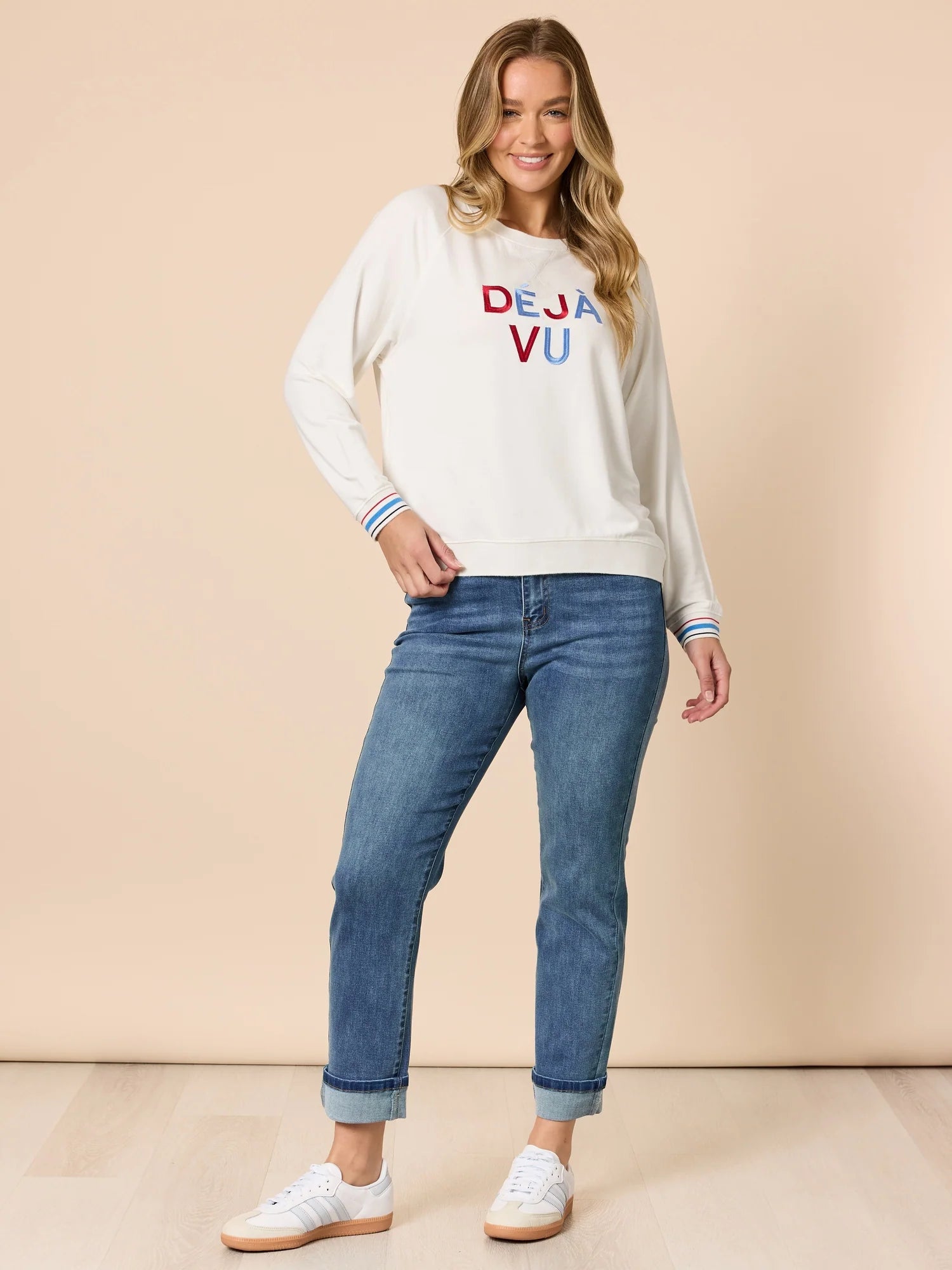 Collection of Woman wearing a Threadz white sweatshirt with colorful text and blue jeans on a beige background in a gallery layout