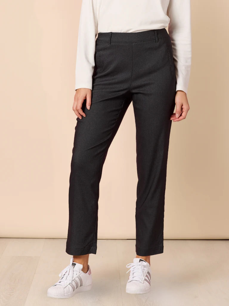 Woman wearing Threadz black pants and white sneakers on a beige background