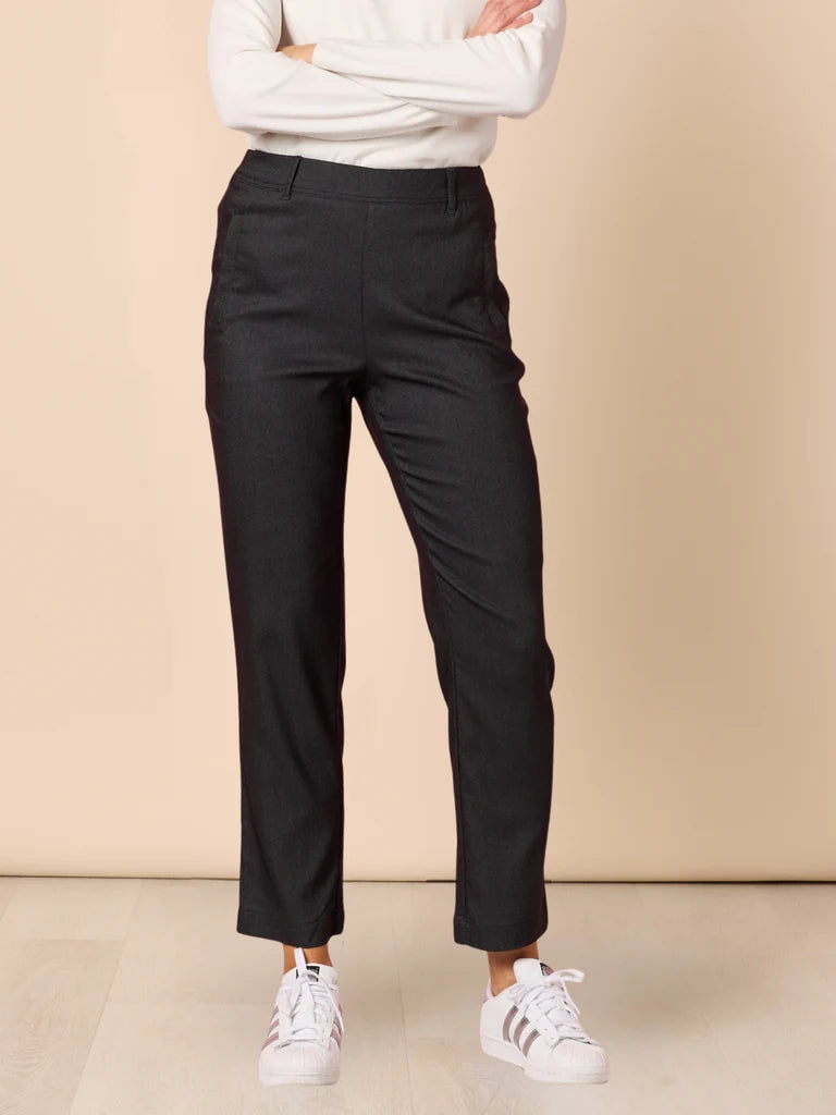 Image of Woman wearing Threadz black pants and white sneakers on a beige background