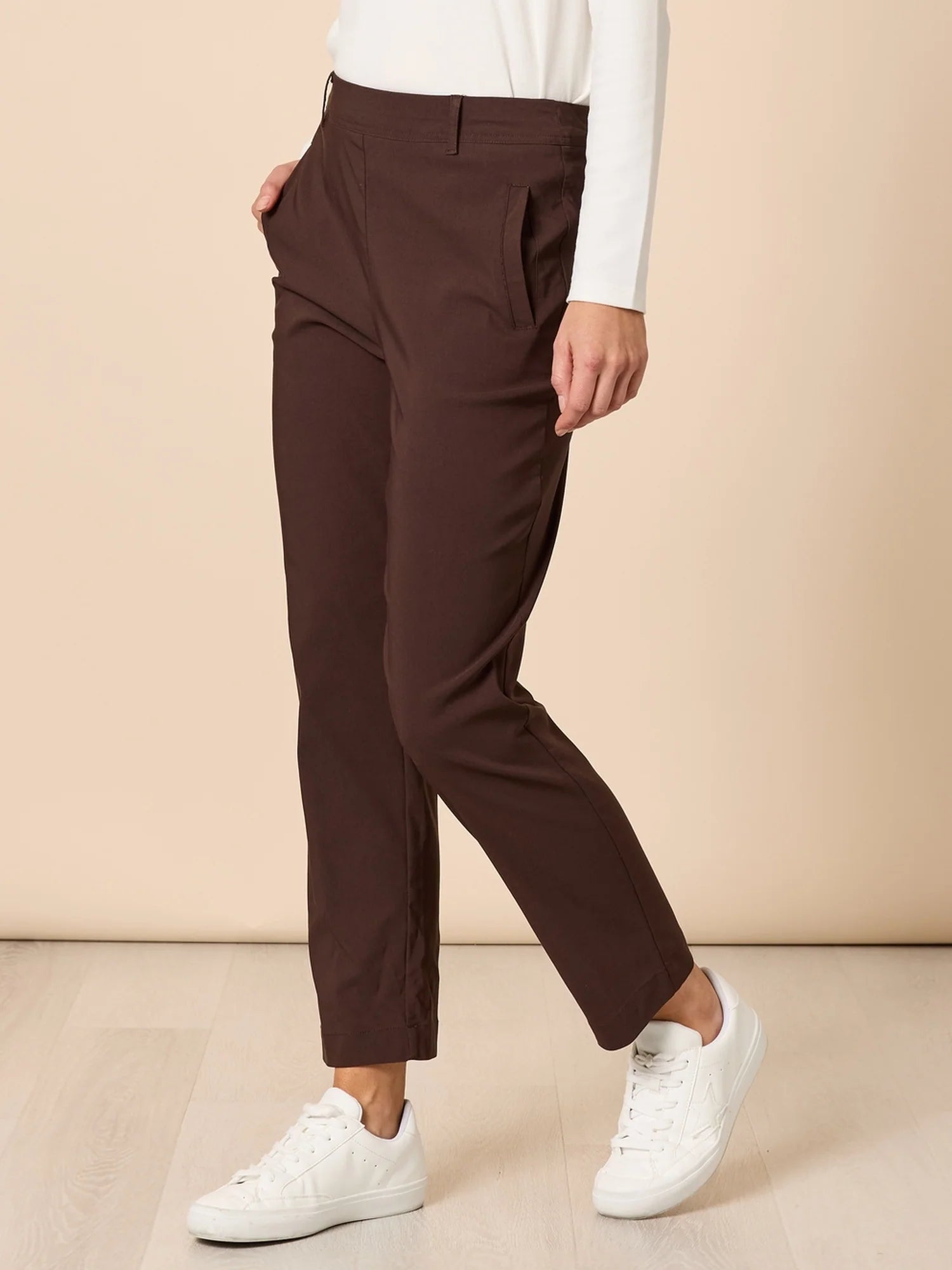 Image of Person wearing Threadz brown pants and white sneakers on a beige background