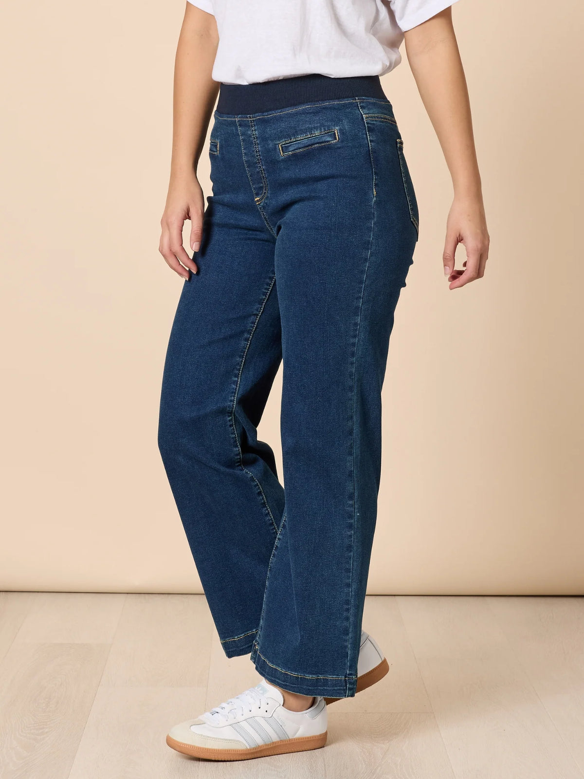 Woman wearing Threadz blue jeans and a white shirt on a beige background