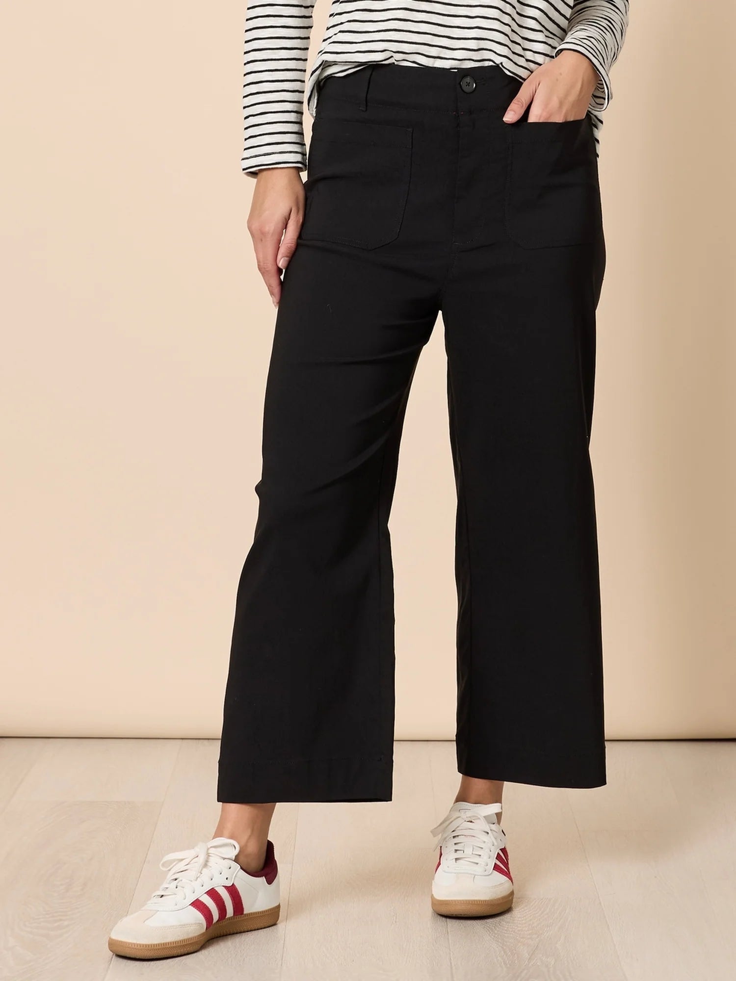 Women wearing Threadz black wide-leg pants with a striped shirt and sneakers on a beige background