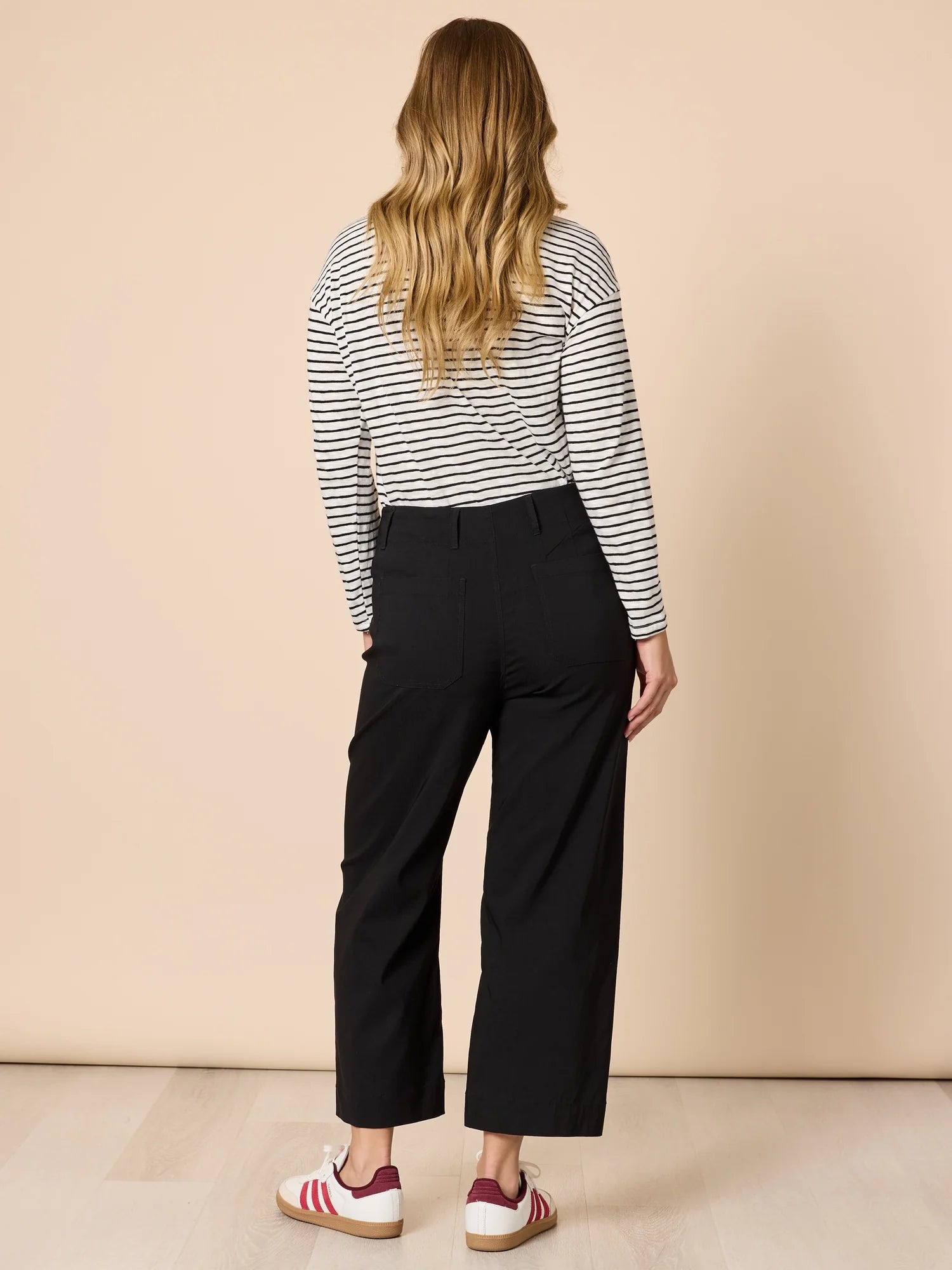 Image of Women wearing Threadz black wide-leg pants with a striped shirt and sneakers on a beige background