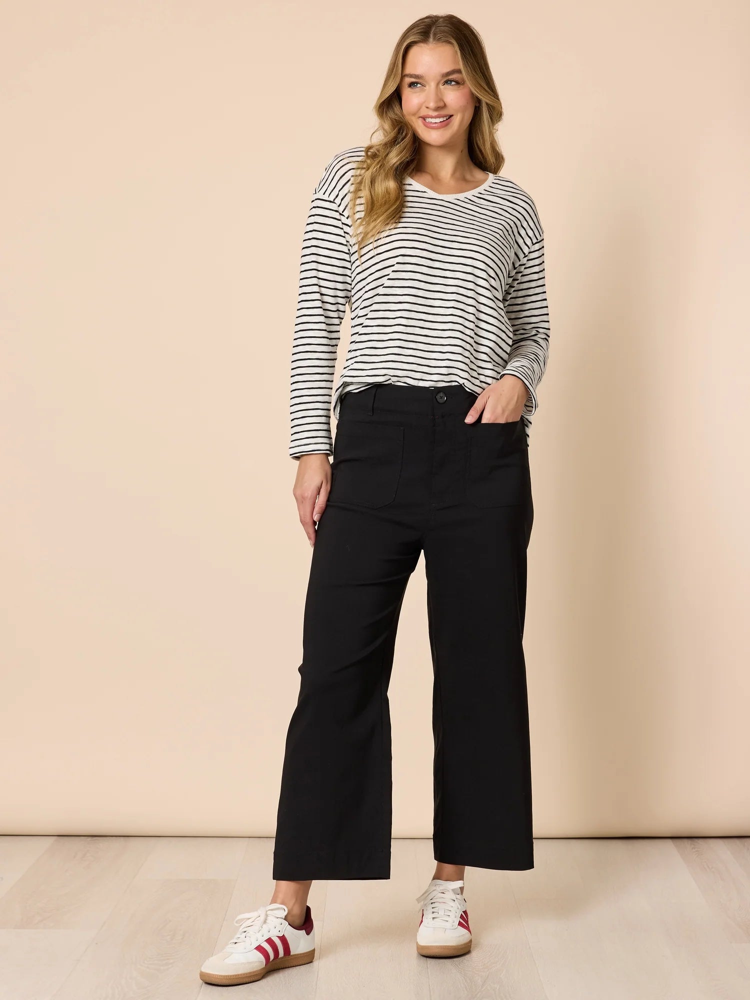 Image of Women wearing Threadz black wide-leg pants with a striped shirt and sneakers on a beige background