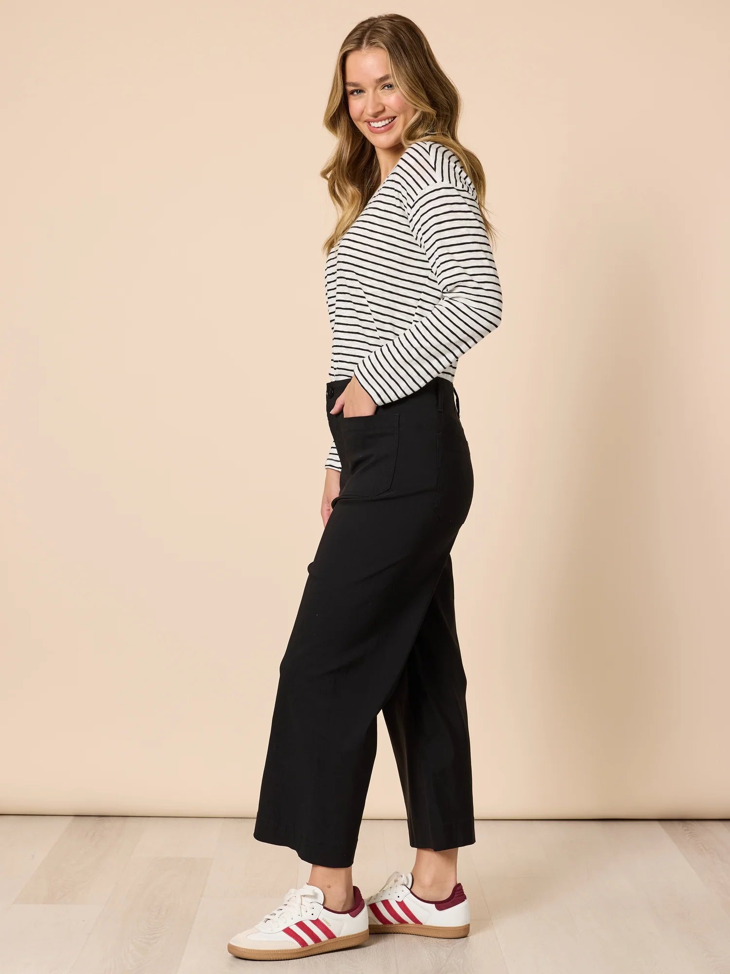 Image of Women wearing Threadz black wide-leg pants with a striped shirt and sneakers on a beige background