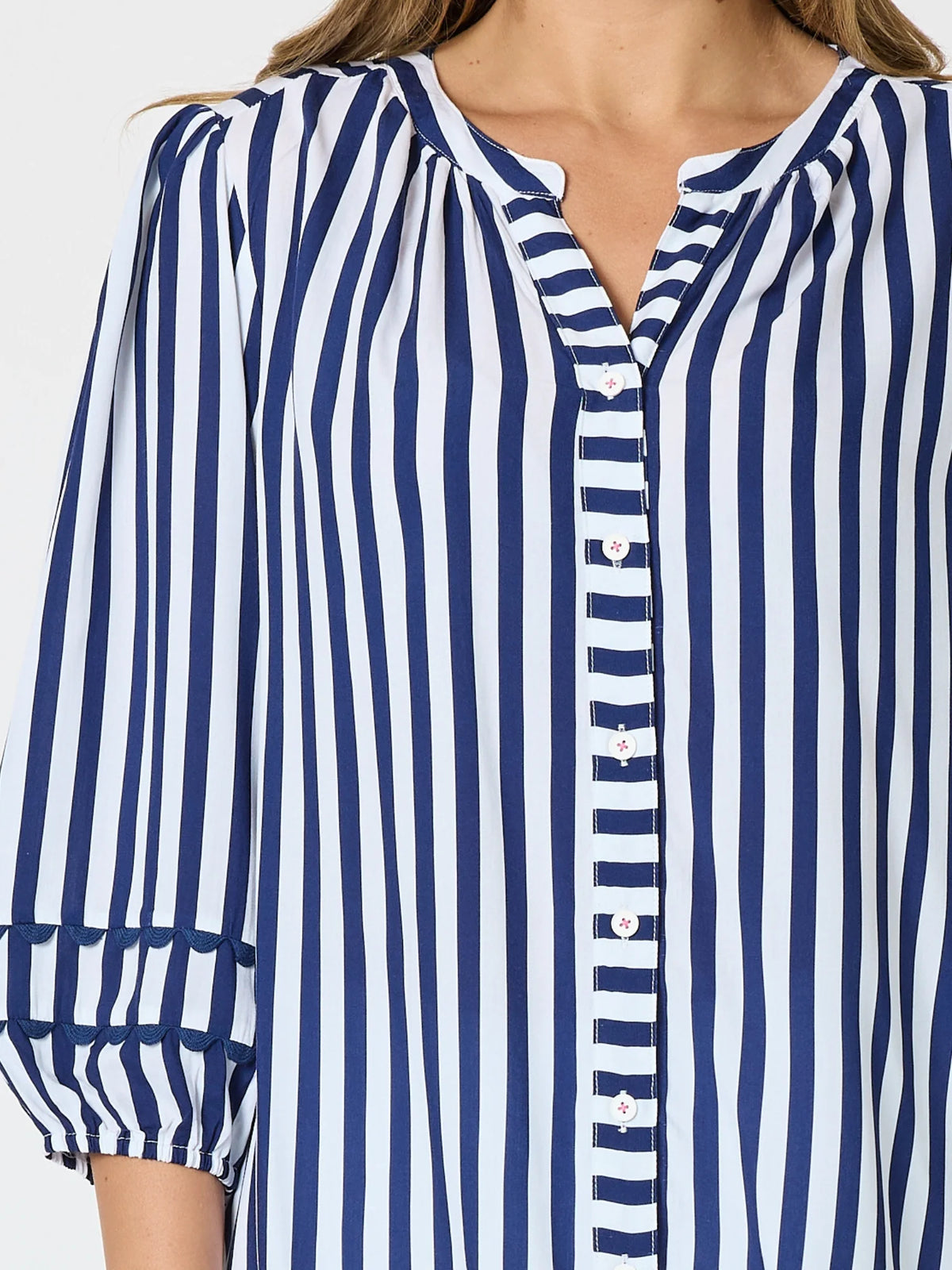 A close-up of a woman wearing a Threadz navy blue and white vertically striped blouse with puff sleeves and a buttoned split neckline.