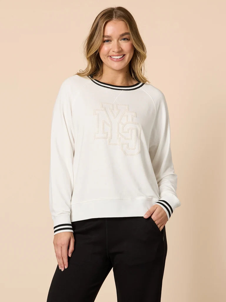 Woman wearing a Threadz white sweatshirt with black trim on a beige background