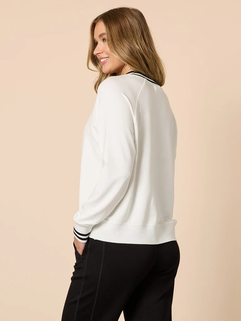 Woman wearing a Threadz white long-sleeve top with black pants on a beige background