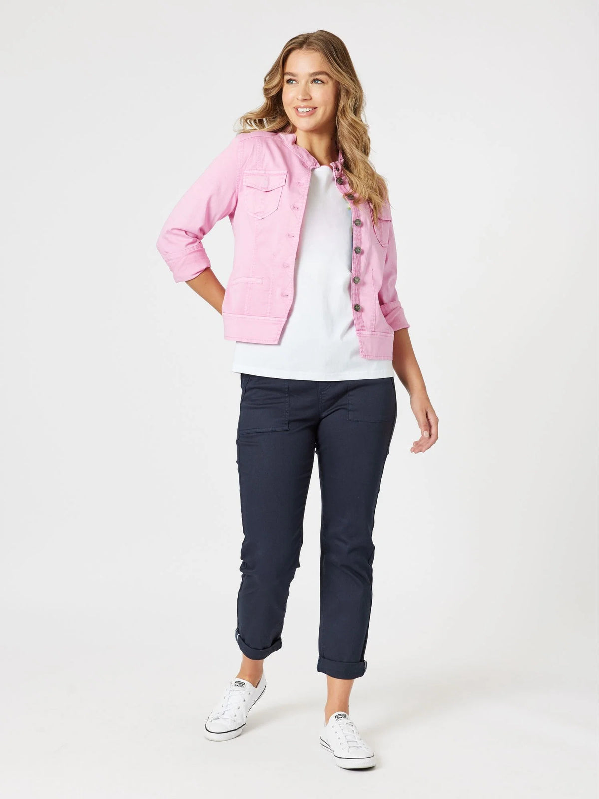 A woman modeling a light pink denim jacket over a white t-shirt, paired with Threadz navy blue cropped pants and white sneakers, against a plain white studio background.