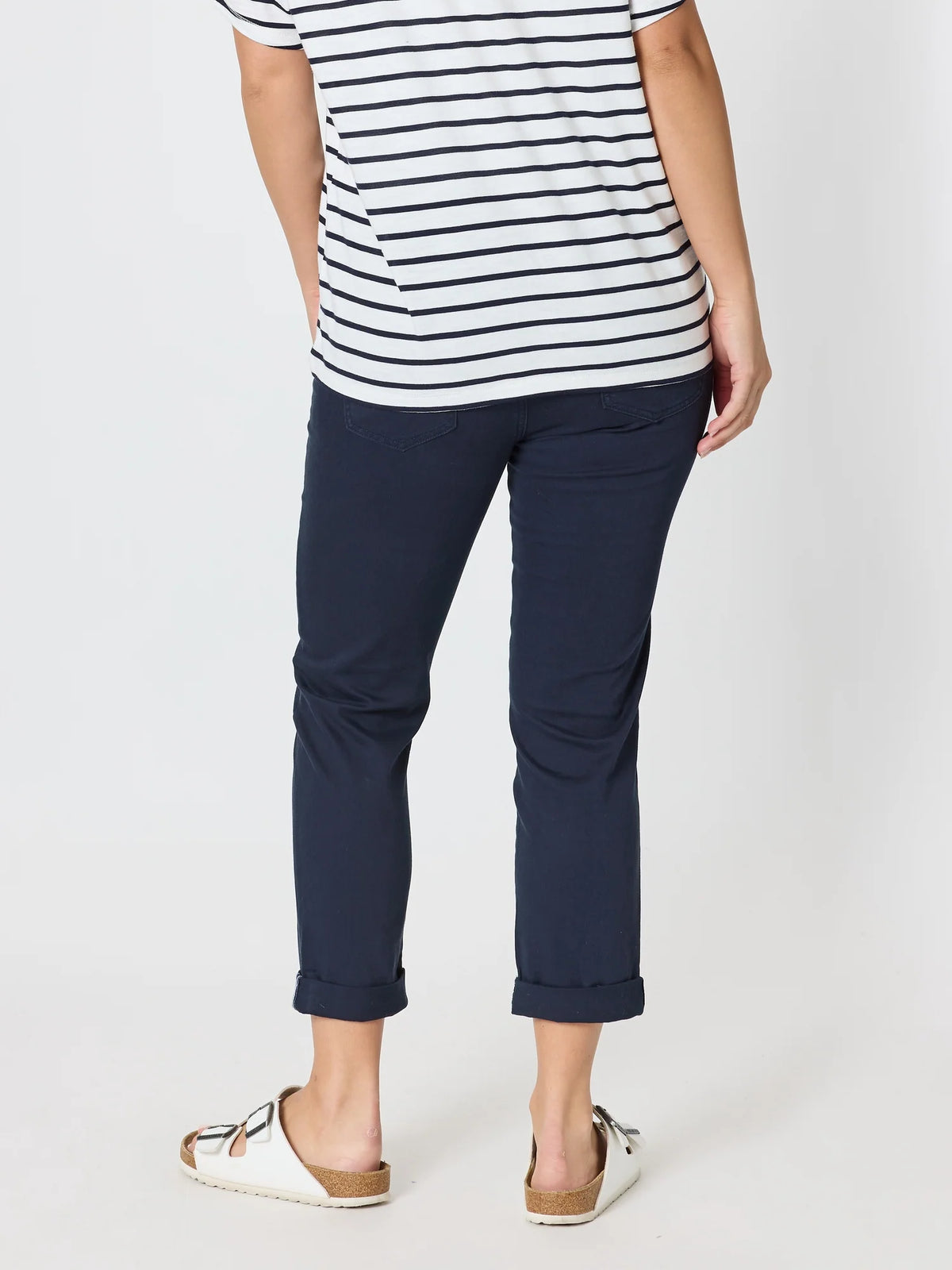 A woman shown from the back wearing Threadz navy cropped pants, a white striped top, and white slide sandals against a light gray studio background.