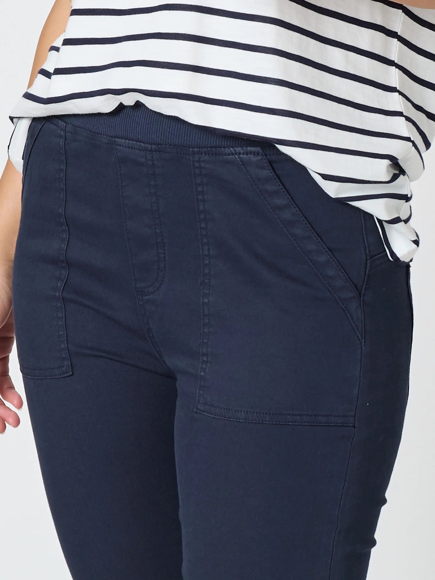 Image of Close-up of a woman wearing Threadz navy blue pants and a white top with navy horizontal stripes, cropped from the chest down against a light gray background.