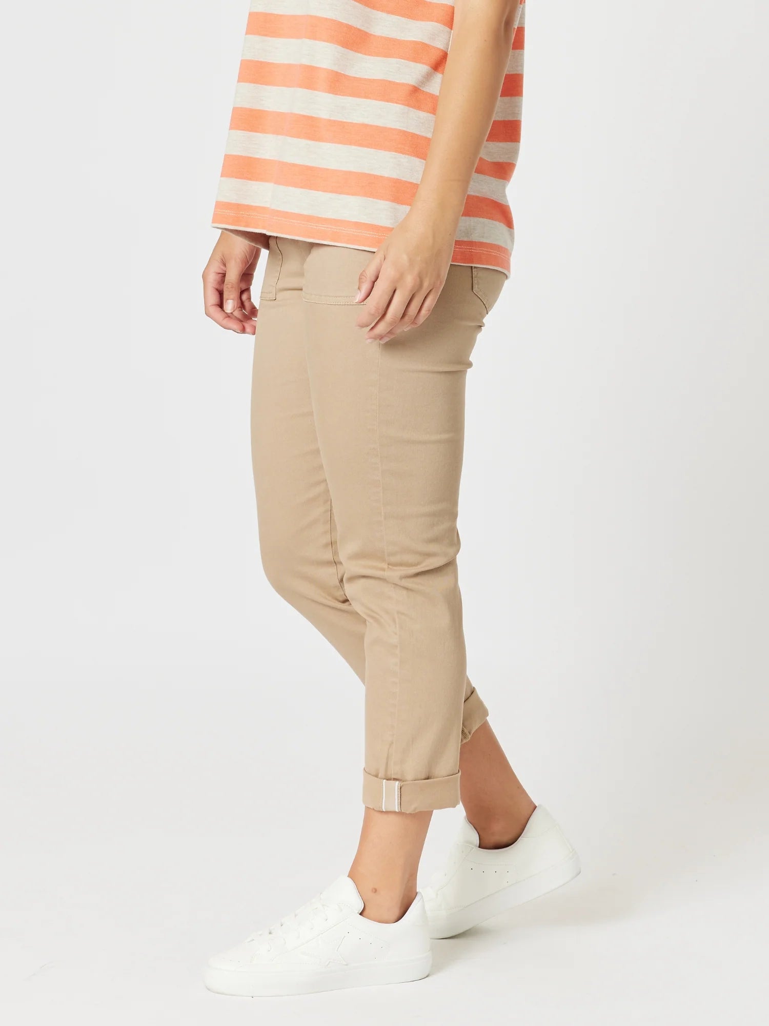 Image of A woman wearing Threadz beige cropped pants with rolled cuffs, paired with a coral and white striped top and white sneakers, shown from the waist down on a light gray studio background.