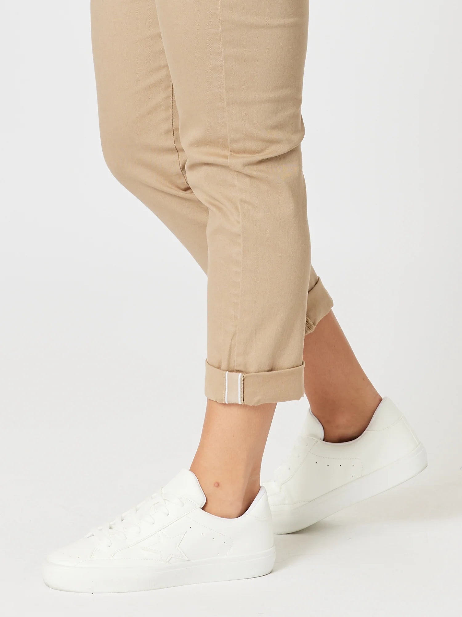 Image of A woman wearing Threadz beige cuffed pants and white low-top sneakers, shown from the knees down against a clean white studio background.