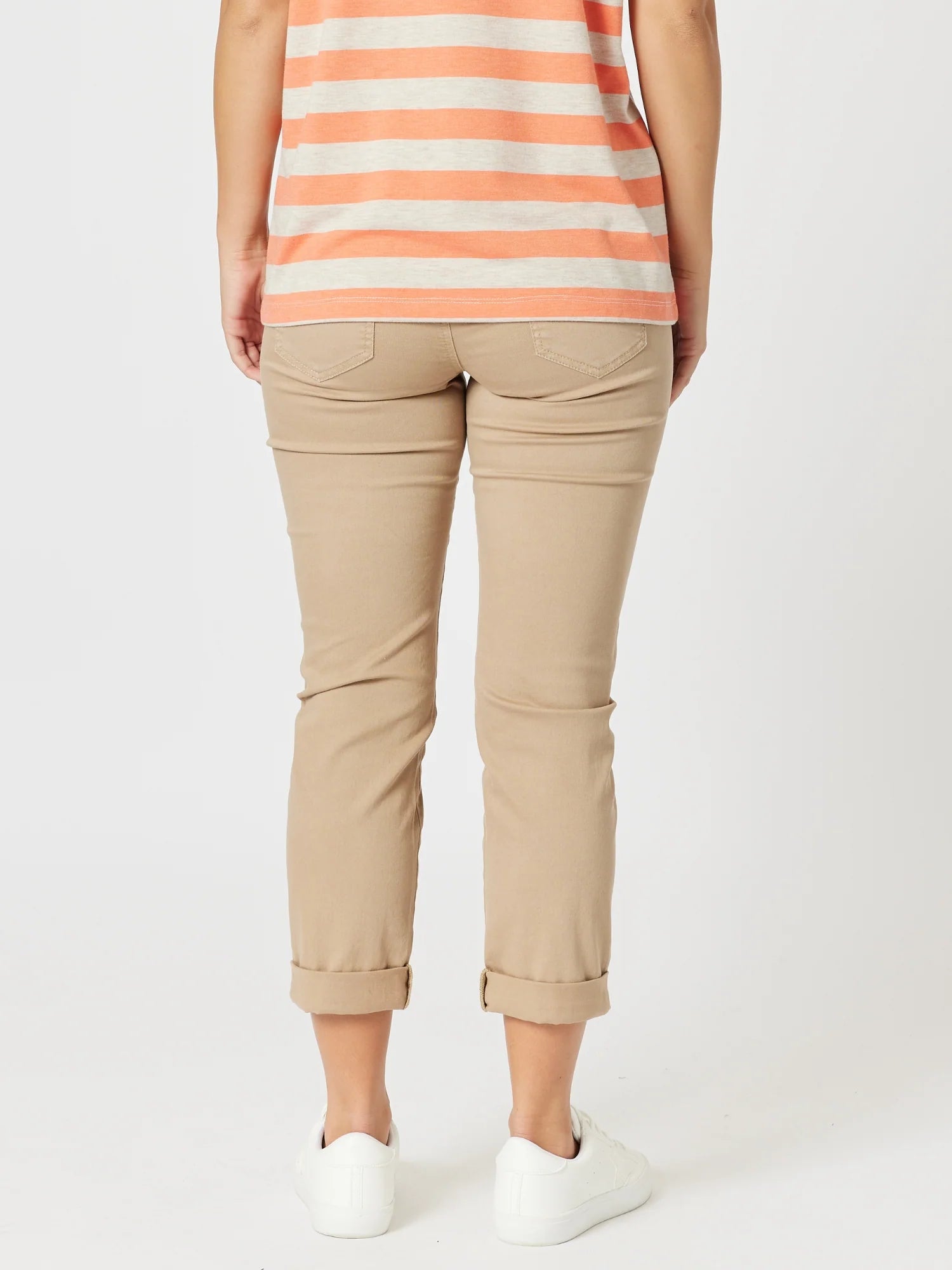 Image of A woman shown from the back wearing Threadz beige cropped pants with rolled cuffs, a peach and cream striped top, and white sneakers against a plain light gray studio background.