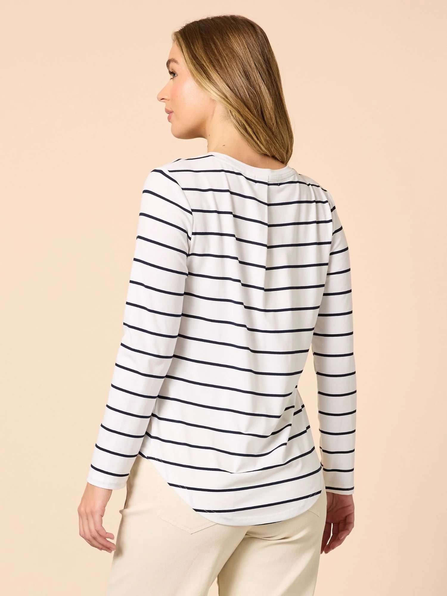 Woman wearing a Threadz white long-sleeve shirt with black stripes on a beige background
