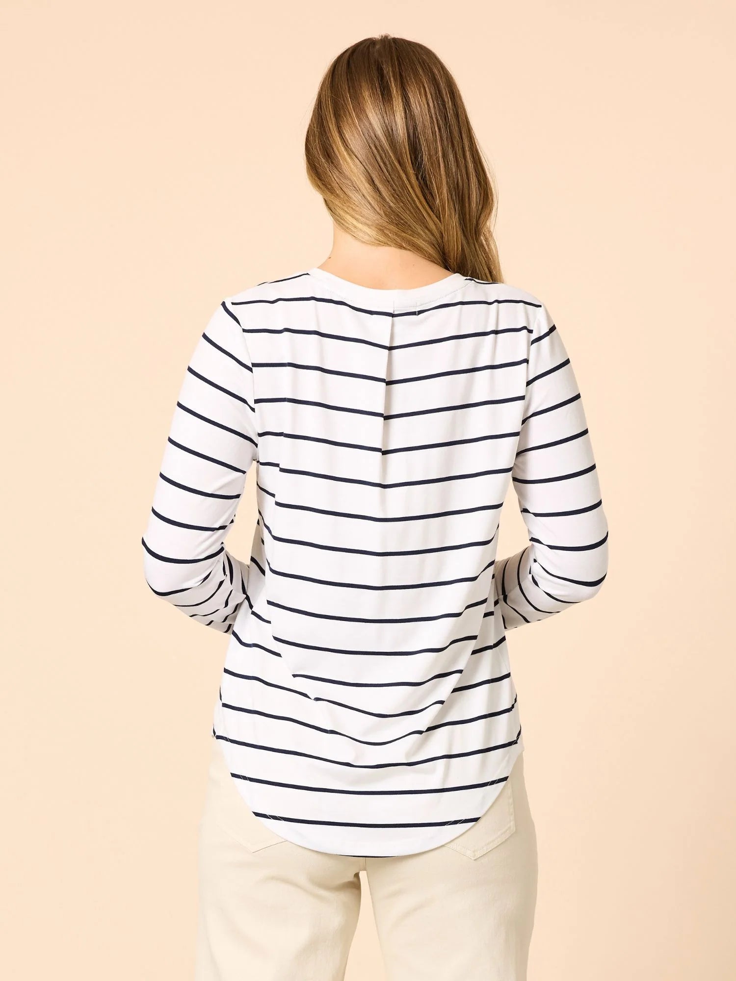 Woman wearing a Threadz striped long-sleeve top on a beige background