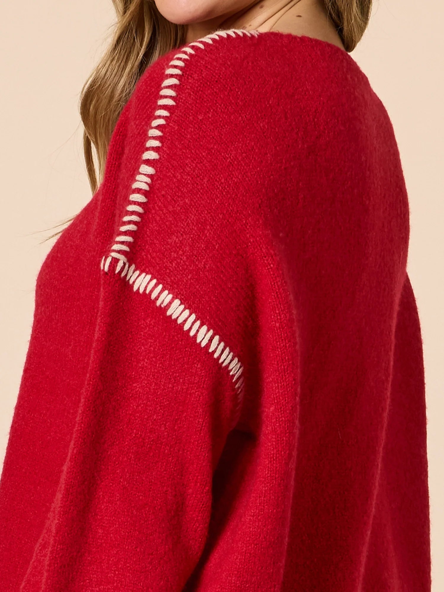 Image of Threadz red sweater with white stitching detail on a beige background