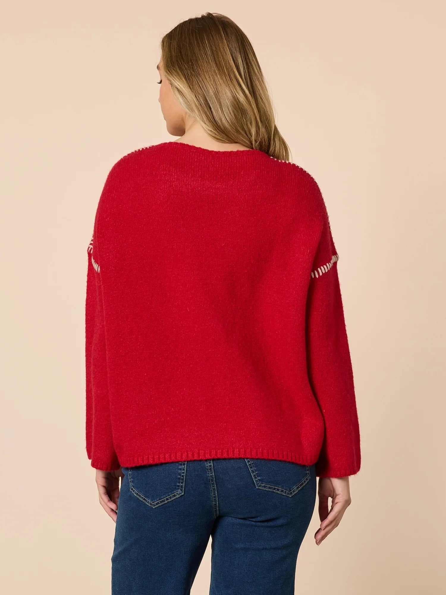 Image of Woman wearing a Threadz red sweater with white patterns on a beige background