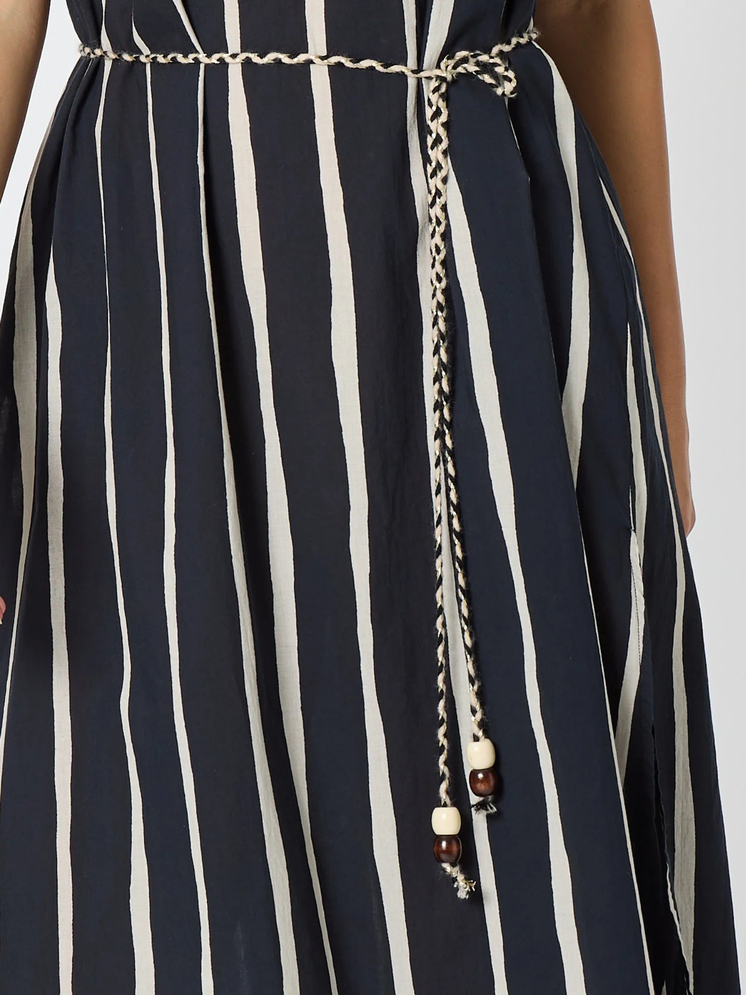 Image of Close-up of a Threadz sleeveless dress with vertical navy and off-white stripes, featuring a matching chain belt tied at the waist with decorative beads.
