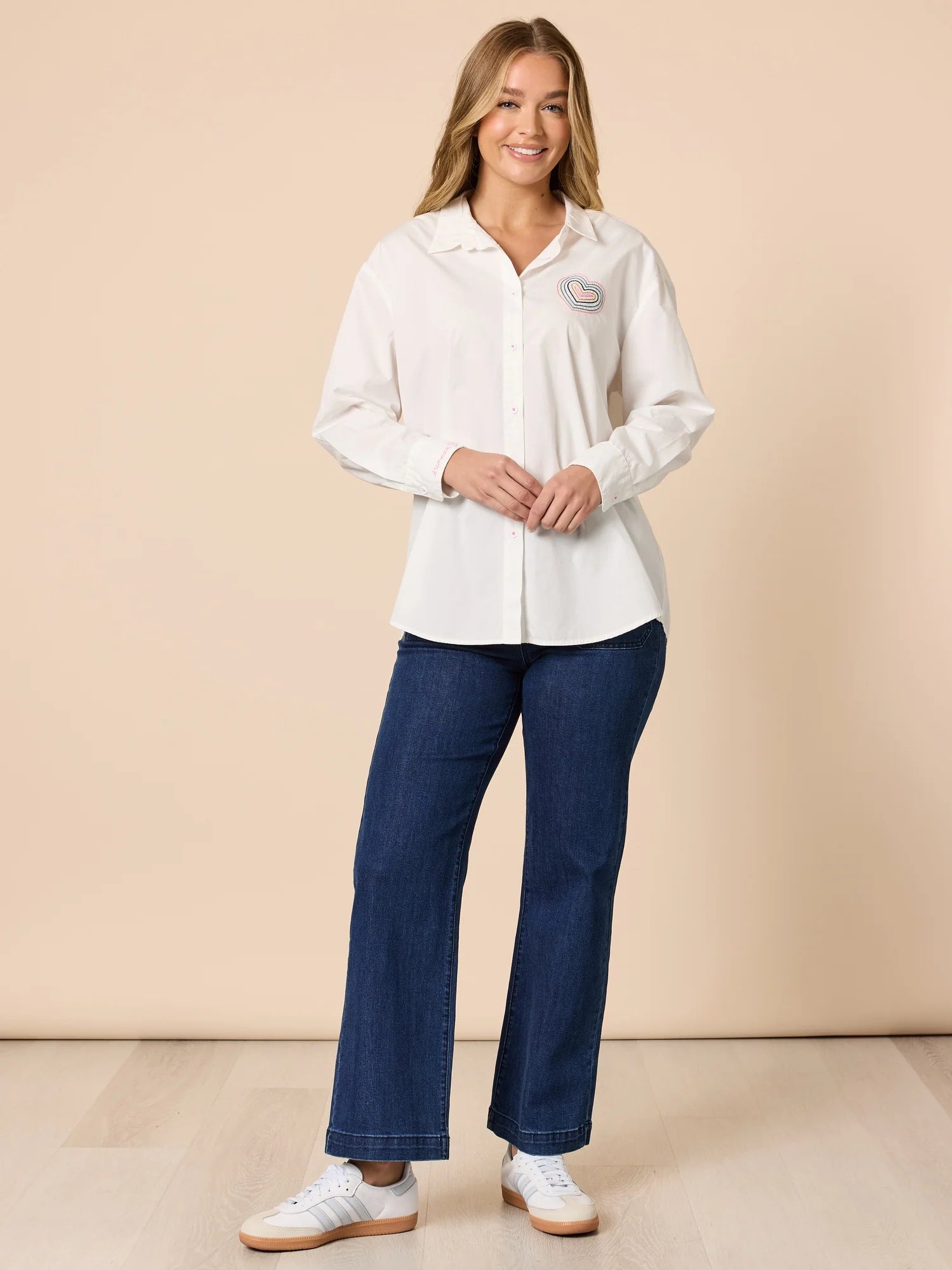 Collection of Woman wearing a Threadz white blouse and blue pants against a beige background in a gallery layout