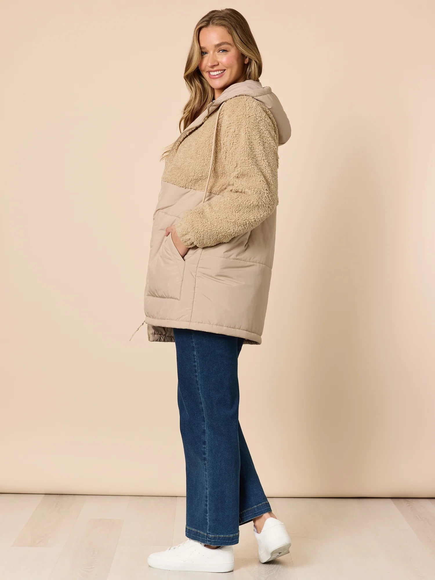 Woman wearing a Threadz beige and brown color-blocked jacket against a beige background