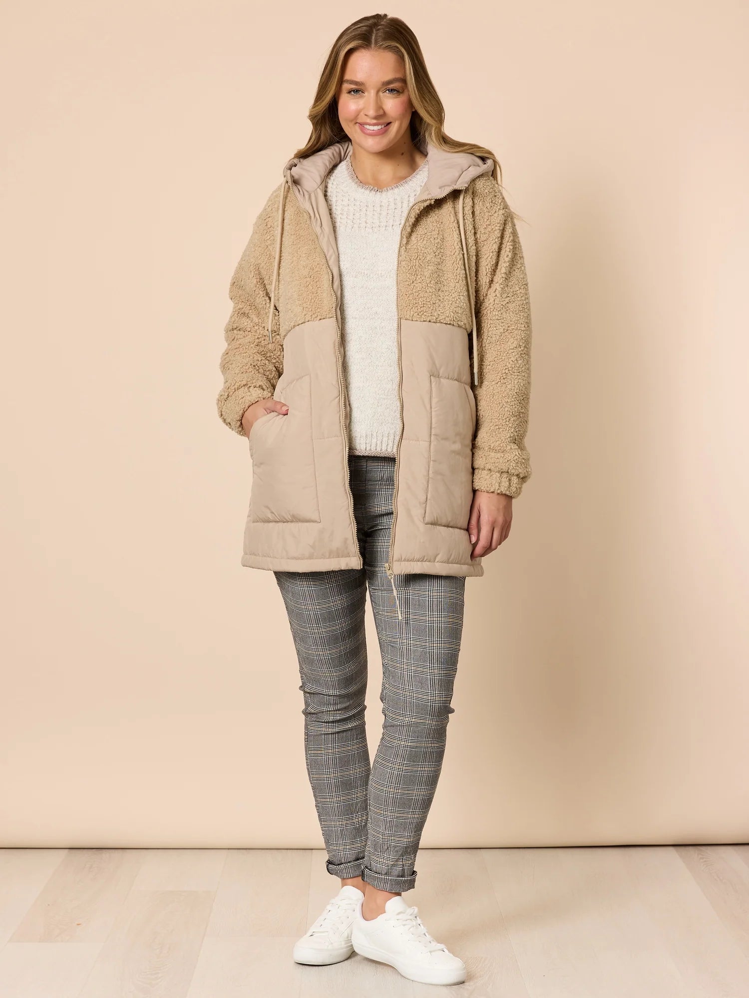 Woman wearing a Threadz beige hooded jacket with a neutral background