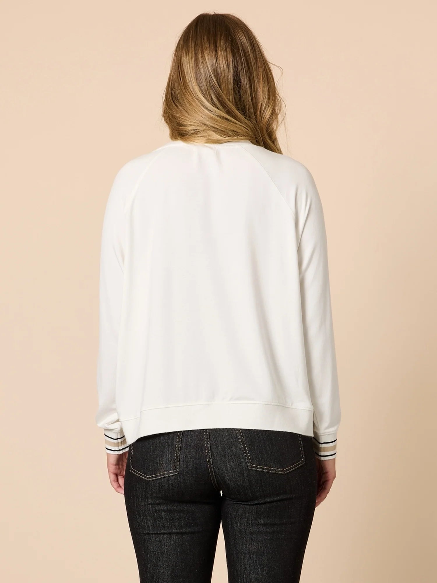 Woman wearing a Threadz white sweatshirt with striped cuffs and hem on a beige background