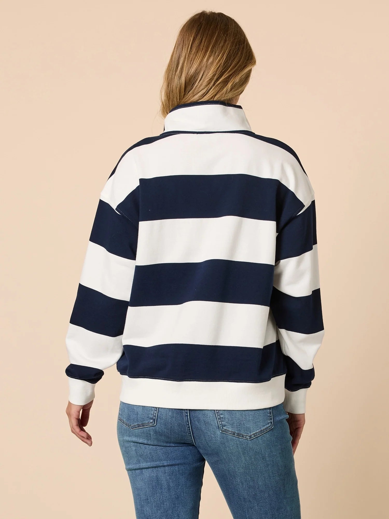 Person wearing a navy and white striped sweater on a beige background