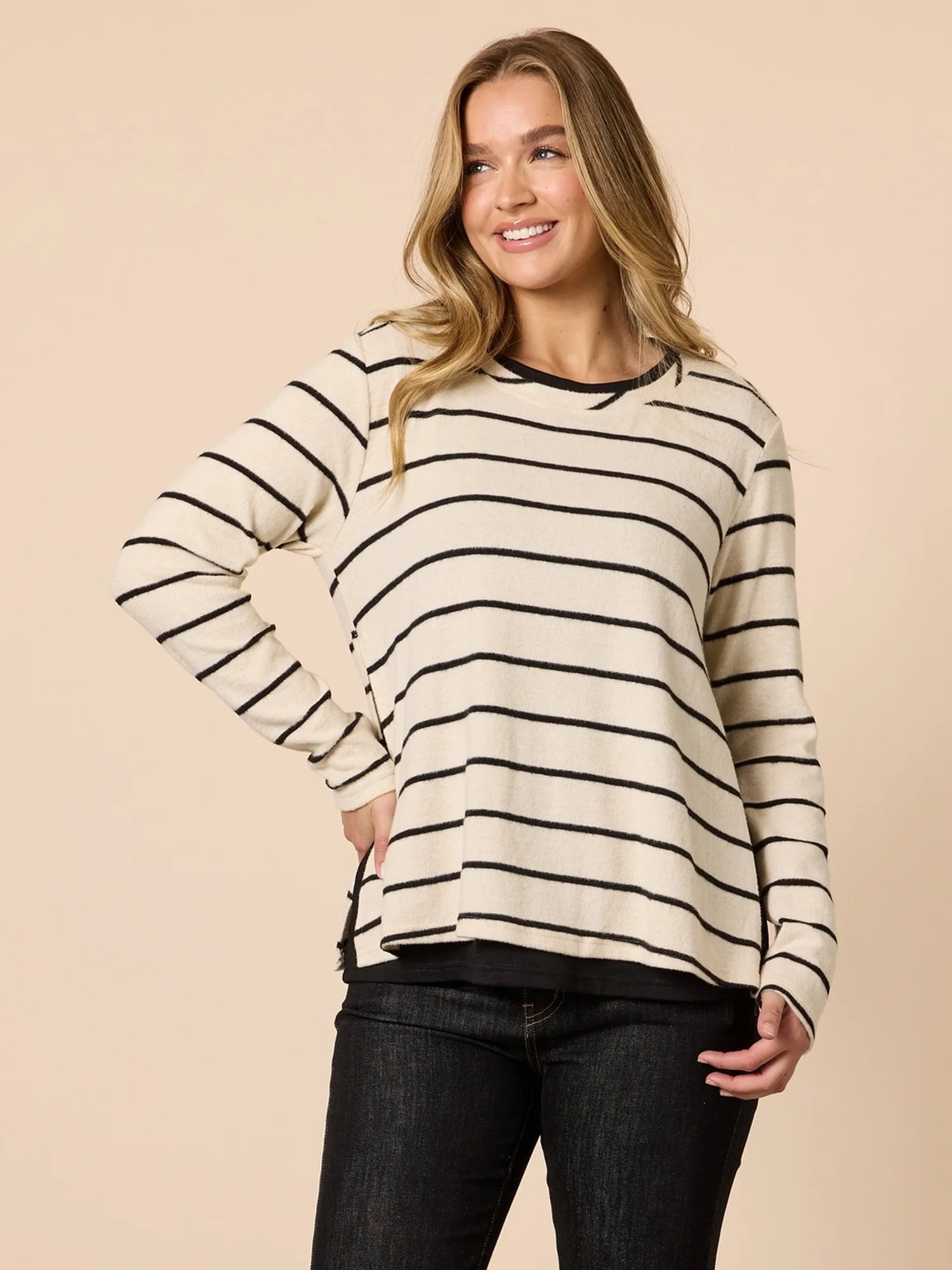 Woman wearing a Threadz striped sweater against a beige background